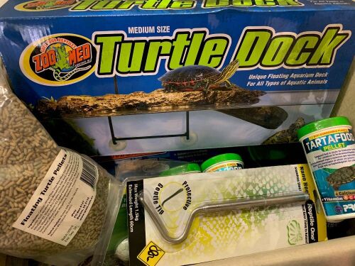 DNL box of assorted turtle enclosure accessories and turtle feeding pellets.