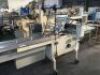 PFM MOTORISED FLOW WRAPPING MACHINE Model: PFM-30 with Approx 200mm Rubber Belt Infeed Conveyor, Take-Out Conveyor, Overhead Wrap Feed-Out Station, Control to 415V 3 Phase Electric Motor and Switch on Mobile Base